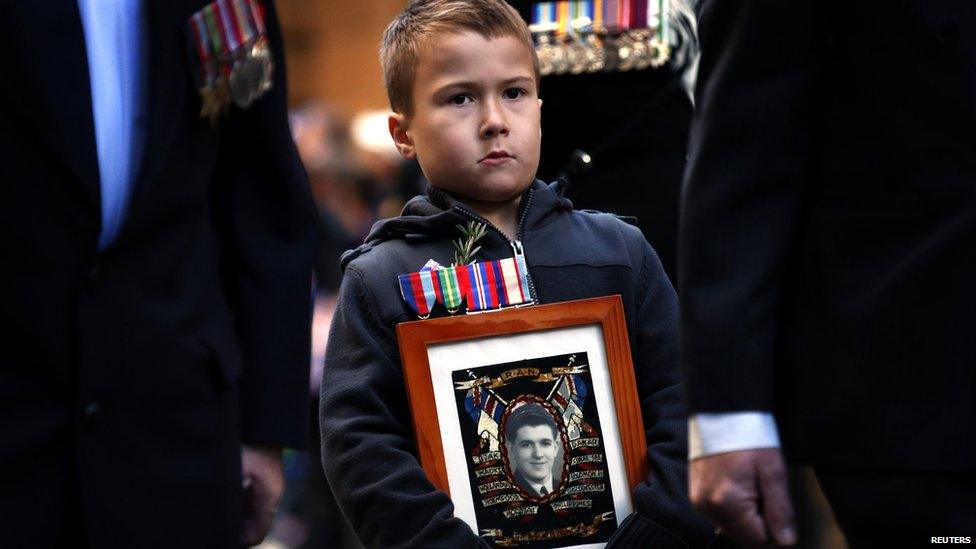 A boy carries a photograph of his deceased grandfather as he marches with veterans during the annual Anzac (Australian and New Zealand Army Corps) Day march in Sydney 25 April 2013