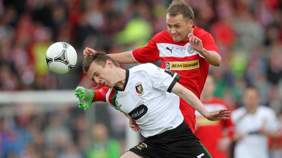 Glentoran defender Jason Hill bravely heads clear to deny Cliftonville's Ciaran Caldwell in Saturday's decider