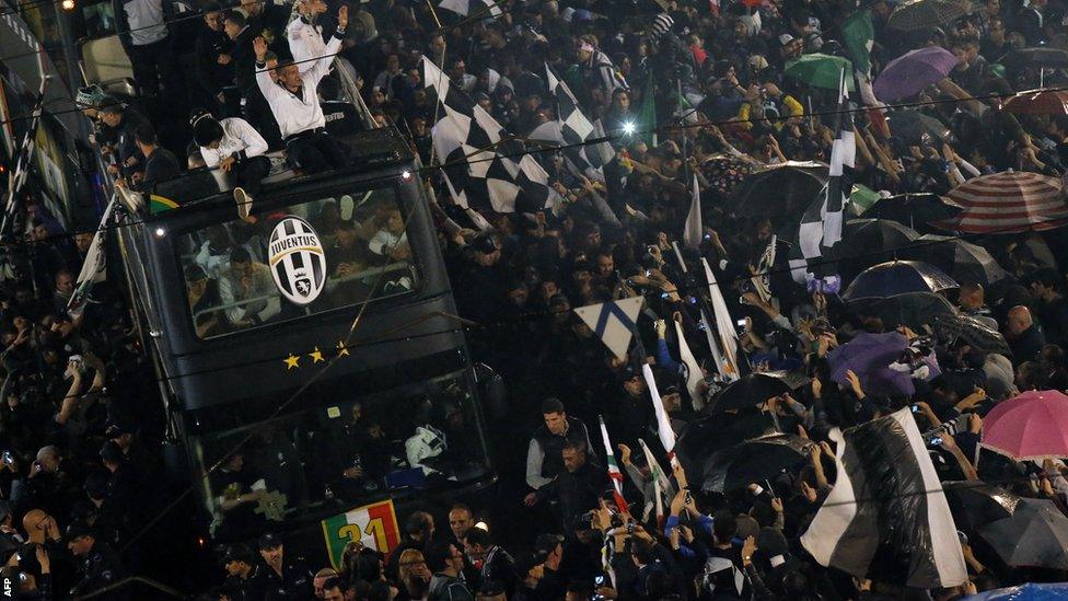 Juventus' players celebrate from the bus in the centre of Turin after winning the 'Scudetto'