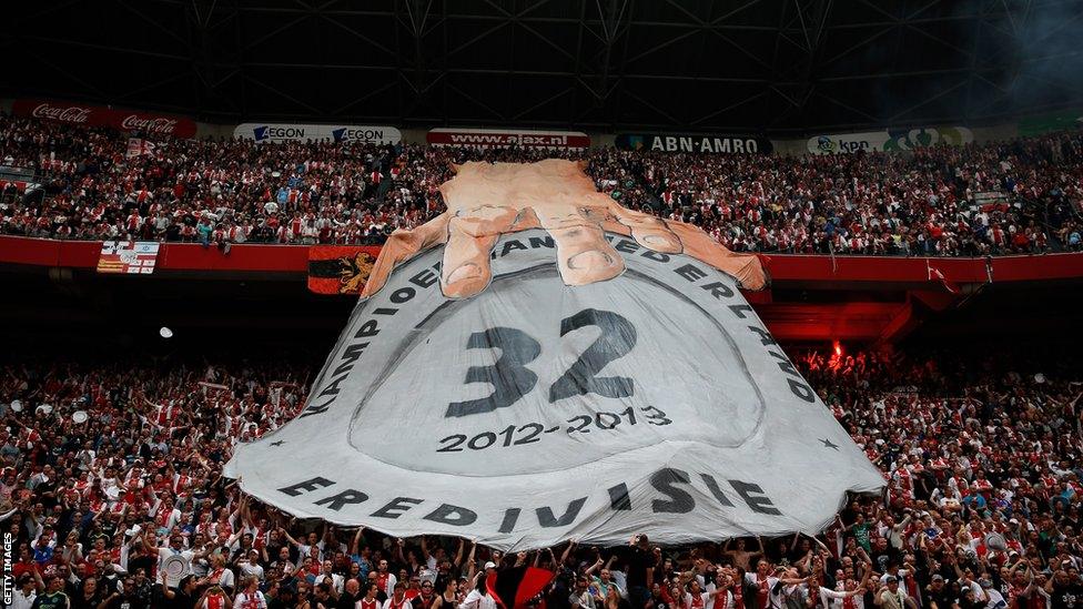 Ajax fans hold a massive banner in Amsterdam Arena showing a hand on their 32nd Dutch title during the Eredivisie match against Willem II Tilburg.