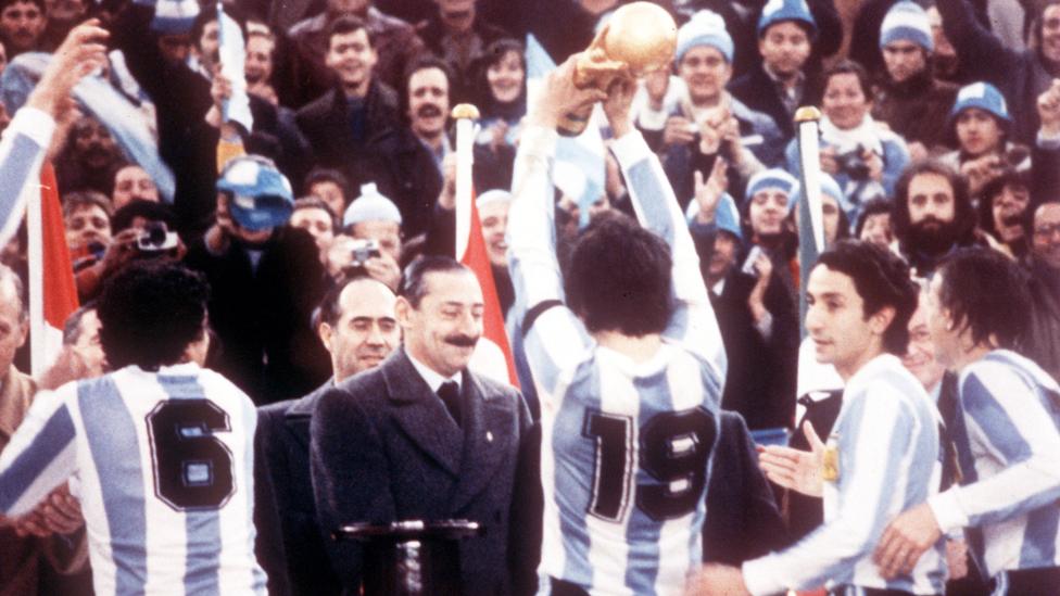 Jorge Rafael Videla (L) presents the World Cup trophy to Argentine national soccer team captain Daniel Passarella after the Argentine vs Netherlands match on June 25, 1978