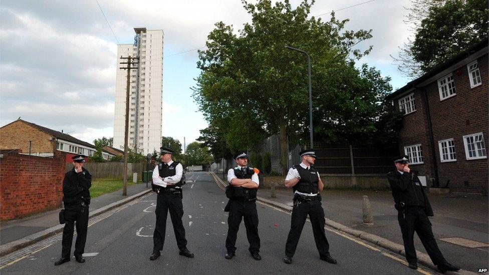 Five police officers block access to a road in Woolwich