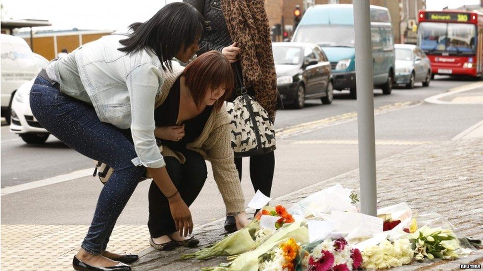 Two women lay flowers in Woolwich