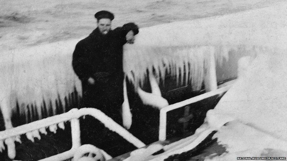 Sailor posing for the camera on-board a ship heavily laden with ice.