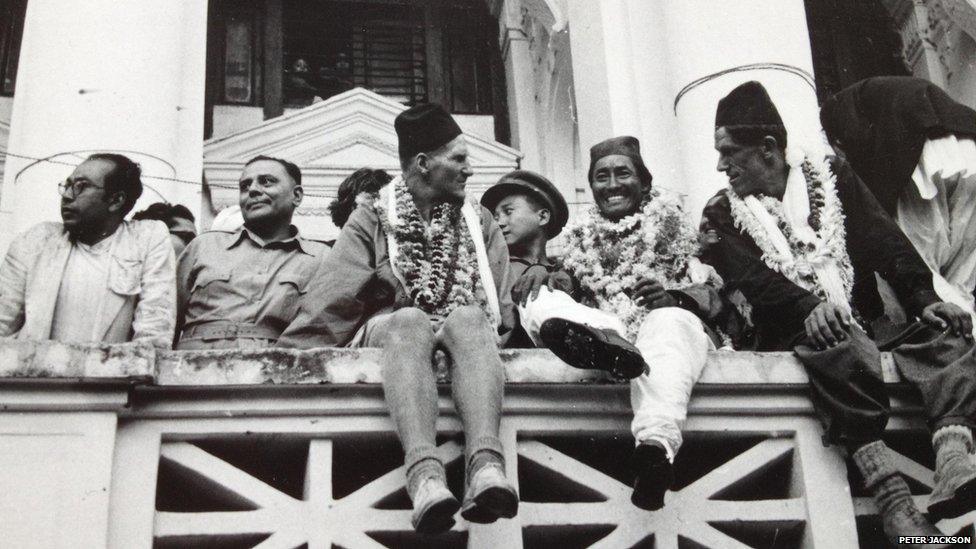 Tenzing and Hillary wearing chains of flowers and sitting on a balcony