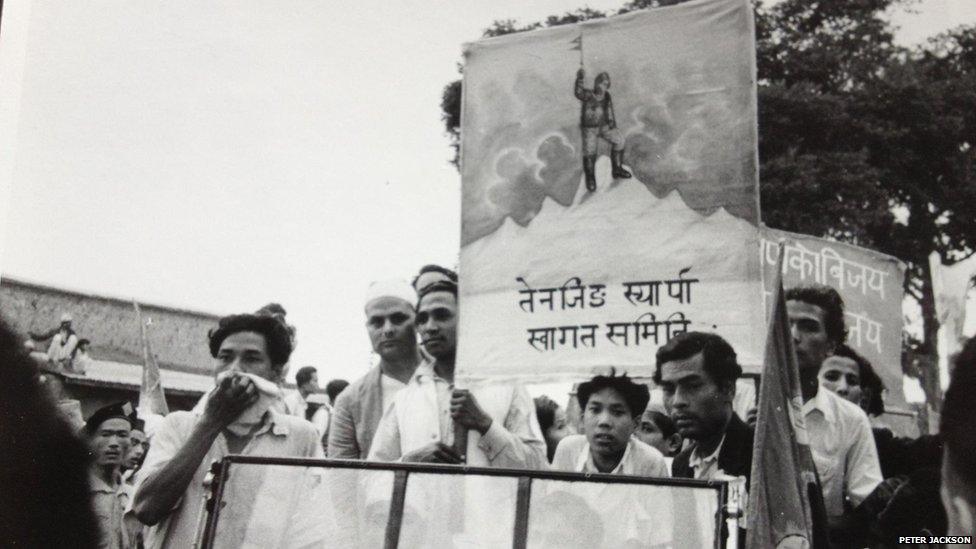 A Nepalese banner, carried by a crowd, depicting Tenzing alone at the top of Mount Everest