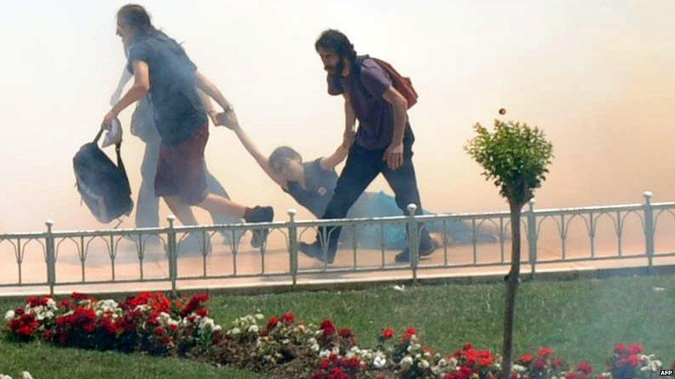 Demonstrators help one another as Turkish riot policemen use tear gas to disperse protesters in Taksim Square, Istanbul, 31 May 2013