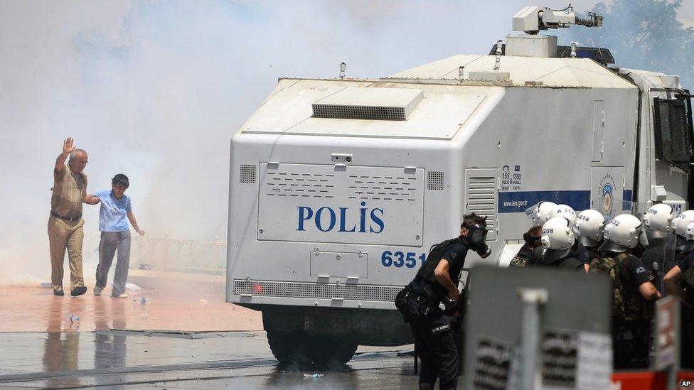 A man helps a boy leave the area after riot police use tear gas and pressurized water in a dawn raid at an Istanbul park, Turkey, 31 May 2013