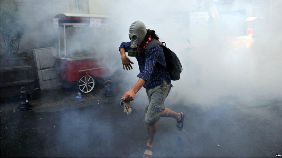 A demonstrator runs with gas mask as Turkish riot policemen use tear gas to disperse protesters, 31 May 2013