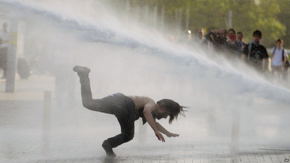 A man falls as riot police use tear gas and pressurized water to quash a peaceful demonstration at an Istanbul park, Turkey, 31 May 2013