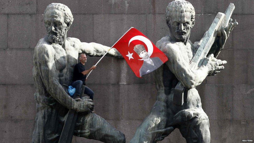 A demonstrator waves Turkey's national flag as he sits on a monument during a protest in central Ankara, 2 June.