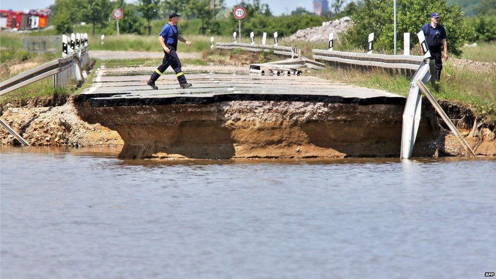 Emergency services workers inspect a road washed away by flood water near Loebnitz, eastern Germany, 7 June 2013