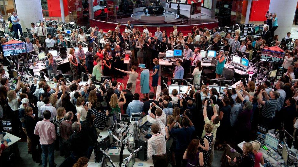 The Queen surrounded by journalists in the BBC newsroom.