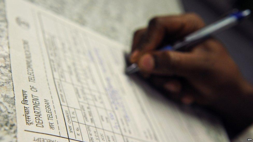 A customer fills in a form for sending out a message using the telegraphic service at a telecommunications office in Bangalore