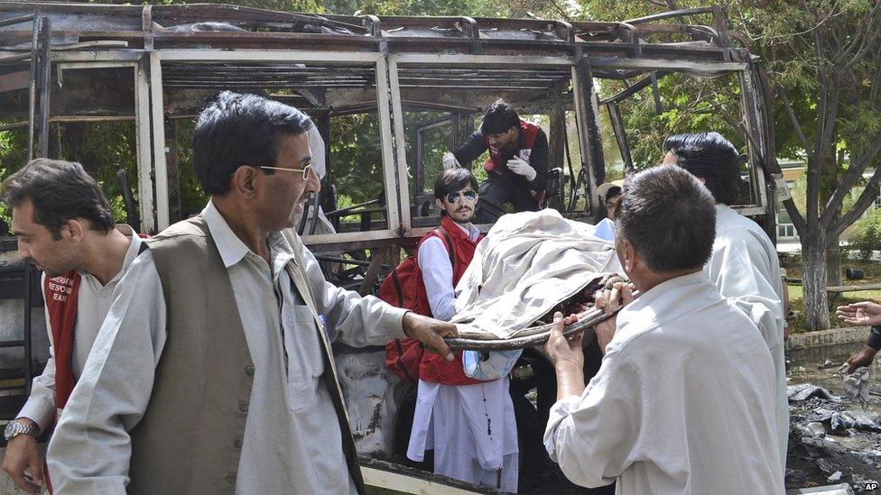 Pakistani police and volunteers gather at the wreckage of a bus destroyed in a bomb blast in Quetta, Pakistan, 15 June