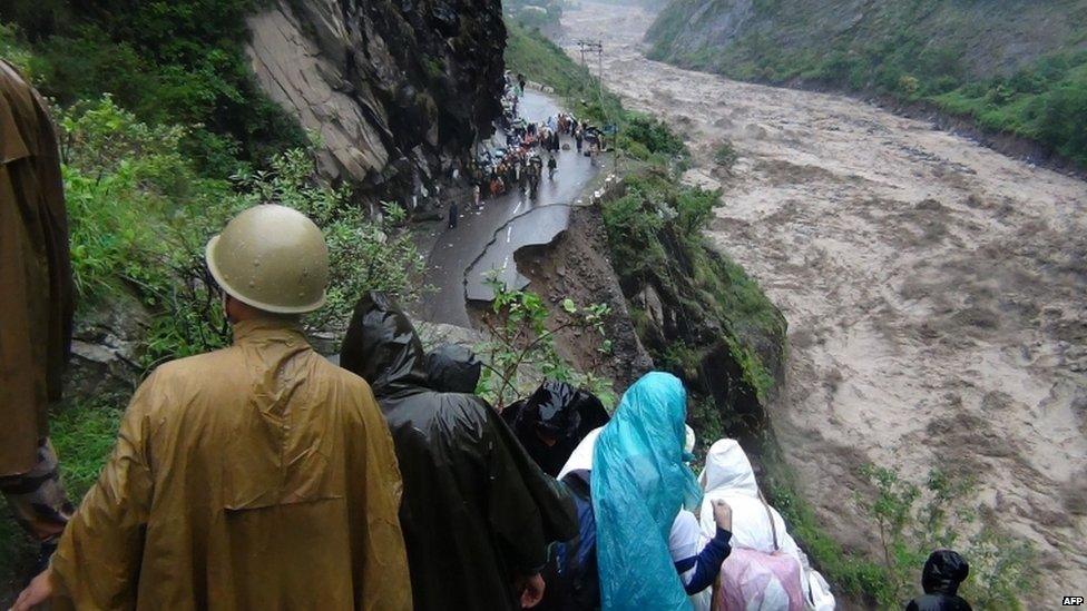 Indian people look at a collapsed road and the flooded river in the northern state of Uttarakhand on June 17, 2013