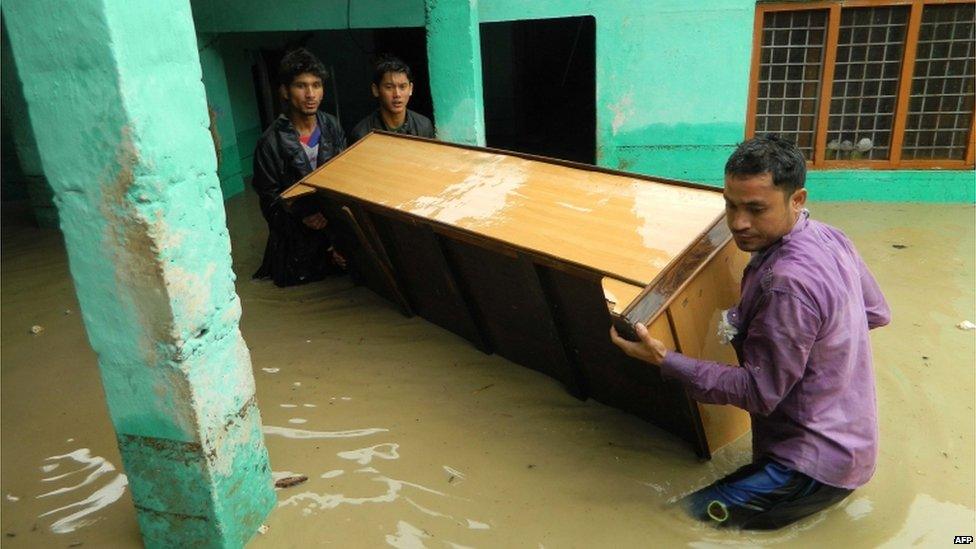 Indian people move furniture as homes floods due to the heavy rains in the northern state of Uttarakhand on June 17, 2013