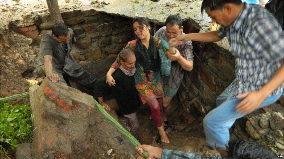 Indian people engage in a rescue operation as homes collapse due to the heavy rains and floods in the northern state of Uttarakhand on June 17, 2013.