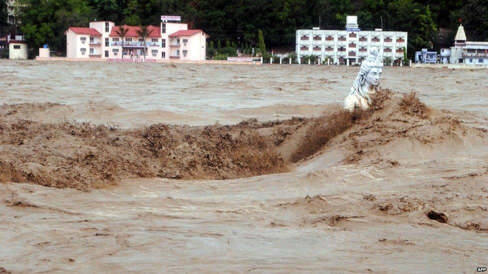 Fast moving water flows over a Hindu statue during a heavy monsoon rain in Rishikesh town in the Indian state of Uttrakhand on June 17, 2013