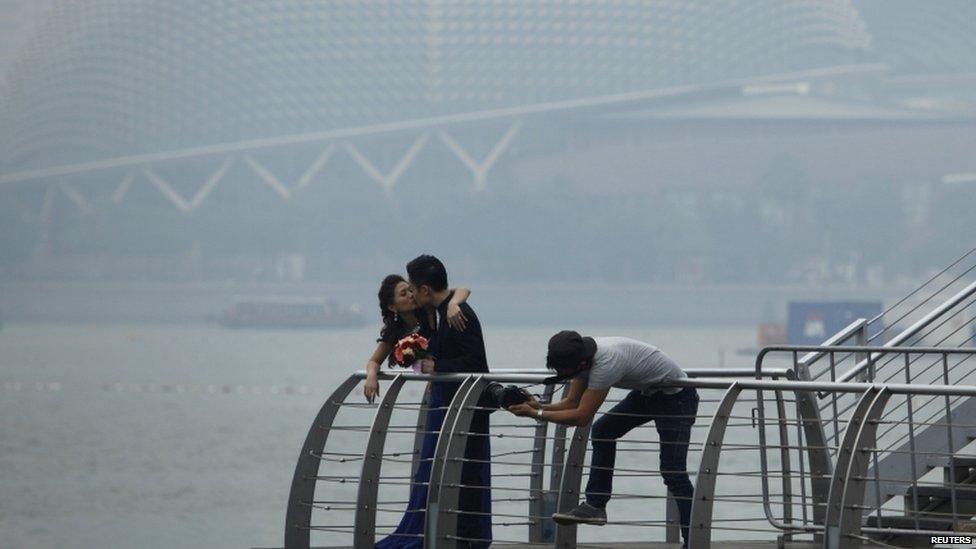 A couple having their wedding photos taken in front of the hazy skyline of Singapore 17 June 2013