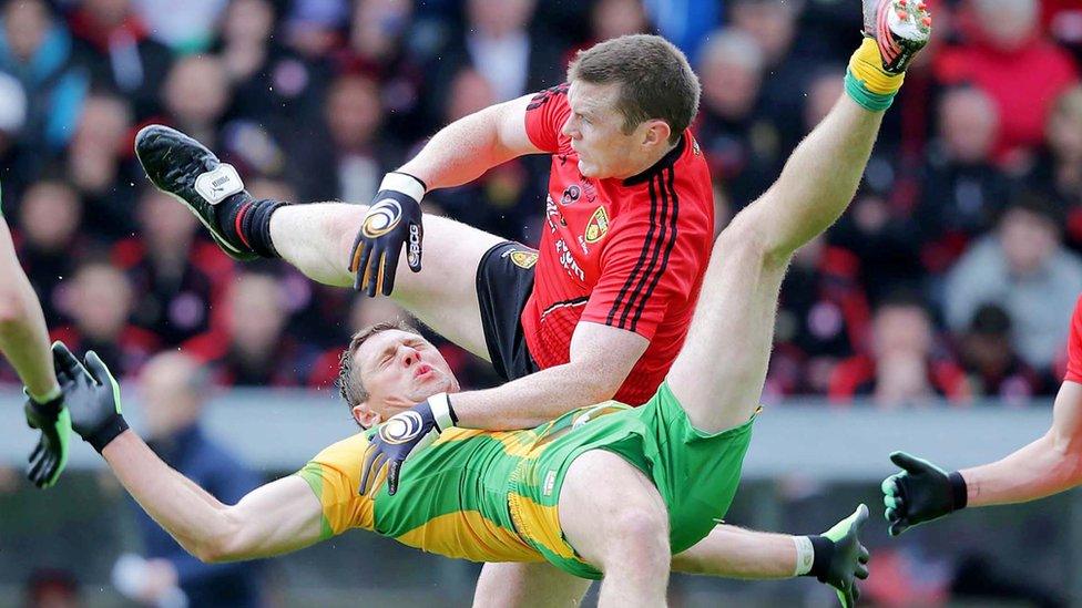 Donegal's Ryan Bradley is sent flying as Calum King of Down challenges for the ball at Breffni Park