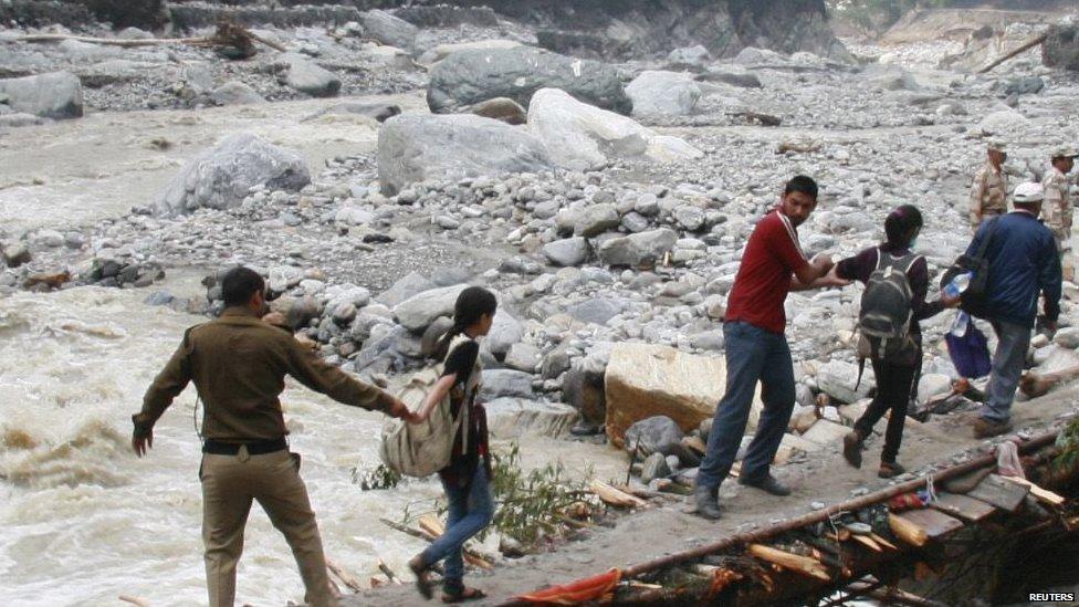 Indian army personnel help stranded people cross a flooded river after heavy rains in the Himalayan state of Uttarakhand 23 June 2013