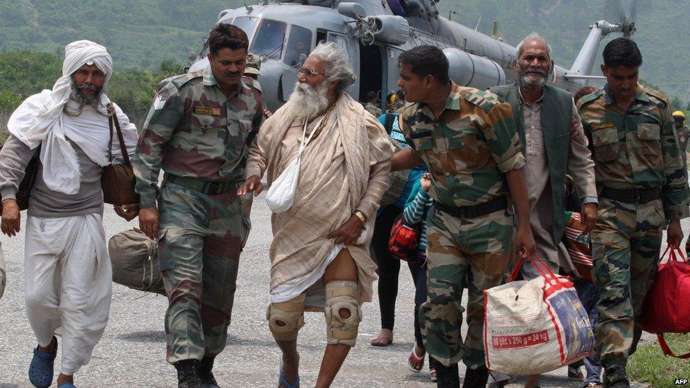 Indian defence personnel assist rescued civilians from the Gangotri area after being flown to safety on board an Indian Air Force Mi-17 transport helicopter at Dharasu in Uttarakhand