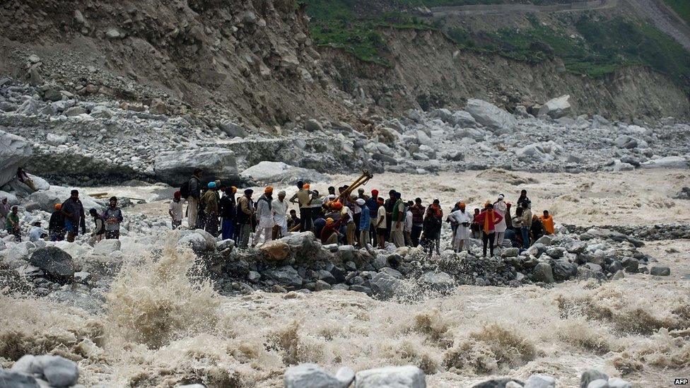 Stranded Indian pilgrims wait to be rescued on the side of a river at Govind Ghat on 23 June 2013