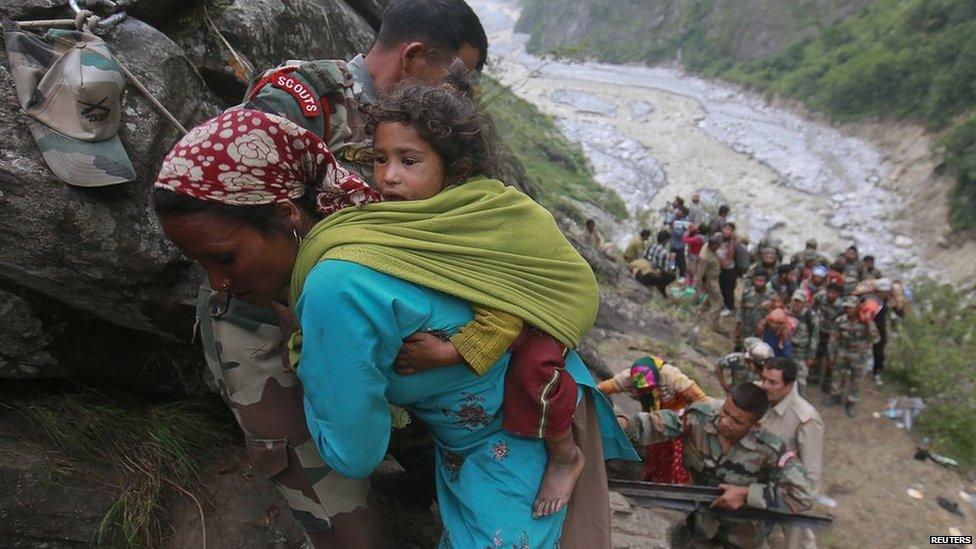 Soldiers assist a woman carrying a child on her back during rescue operations in Govind Ghat in the Himalayan state of Uttarakhand on 23 June 2013