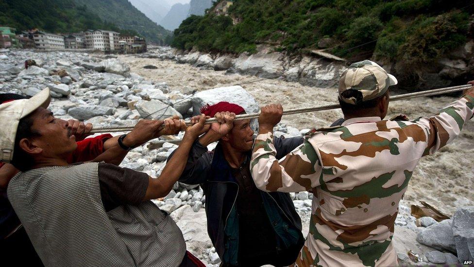 Indo-Tibetan Border Police (ITBP) personnel and local residents pull a rope to rescue stranded pilgrims on the other side of a river at Govind Ghat on 23 June 2013