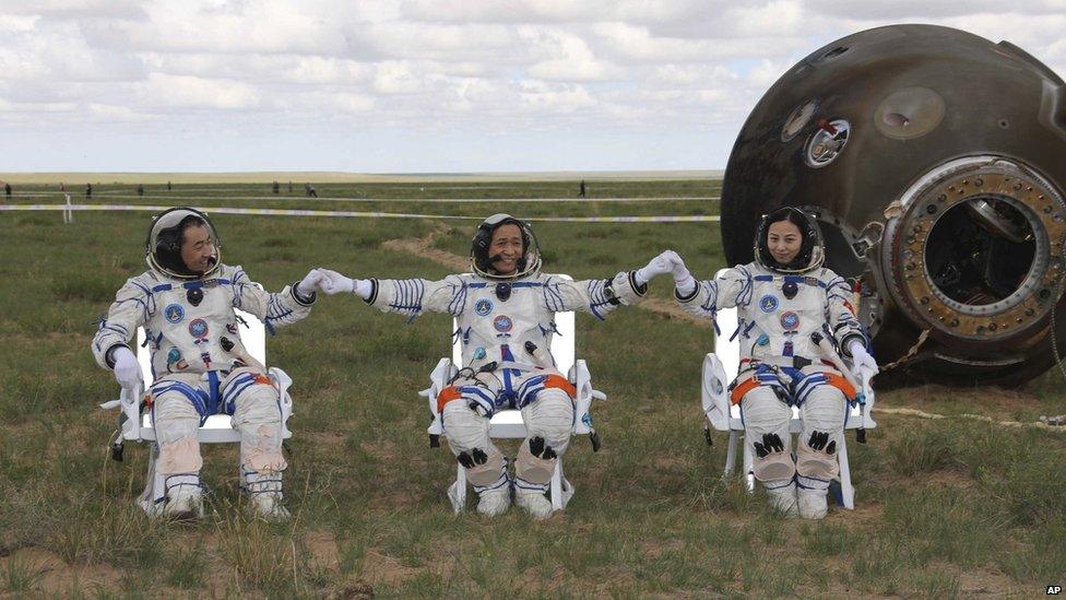 Astronauts Zhang Xiaoguang, Nie Haisheng and Wang Yaping (L to R) join hands after successfully landing back on Earth on 26 June 2013