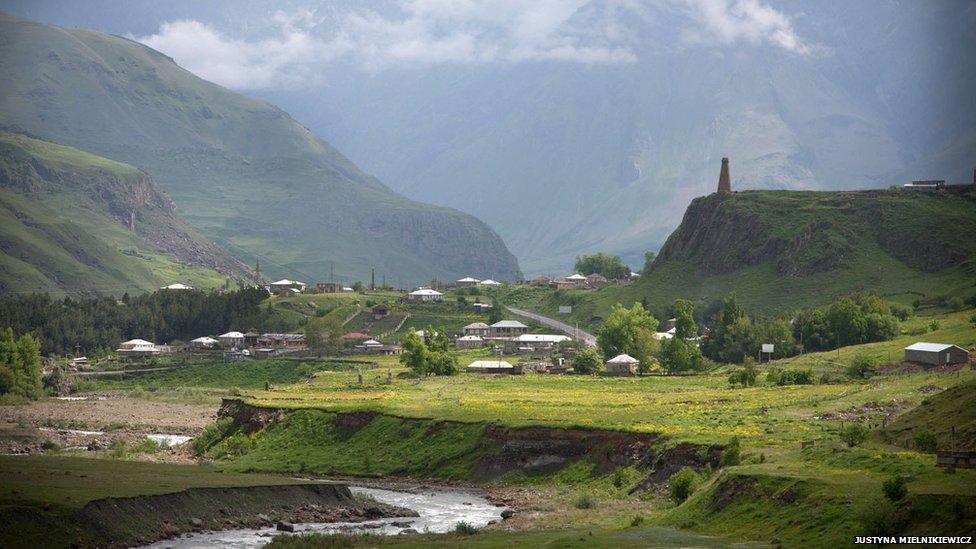 View of the Georgian Military Highway with dramatic mountain scenes in the distance. The road leads to the Russian border to the north.