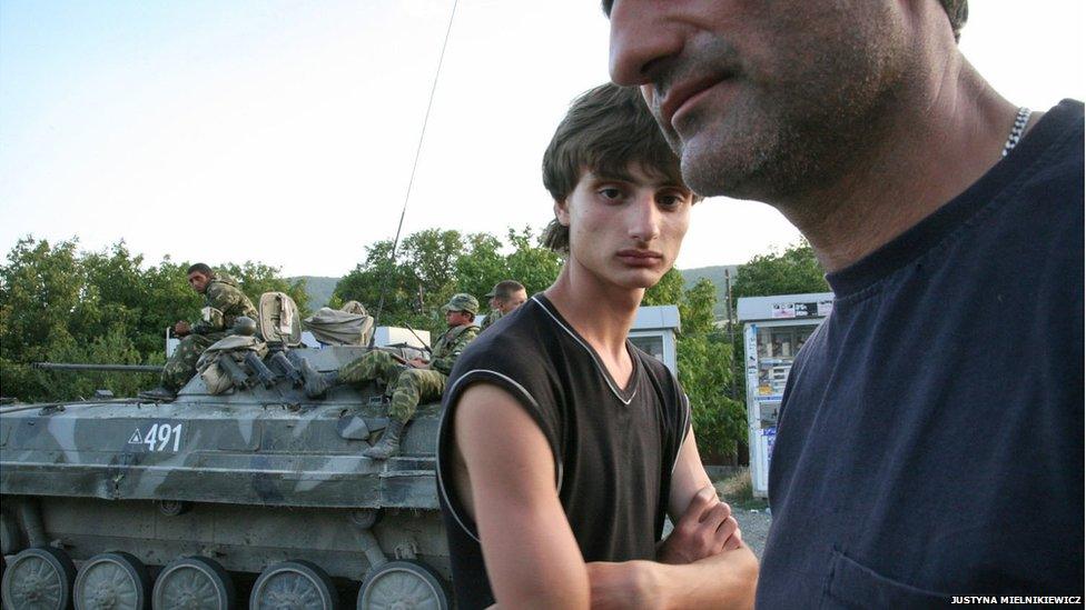 Father and son stand next to a Russian armoured vehicle during the 2008 conflict between Georgia and Russia.