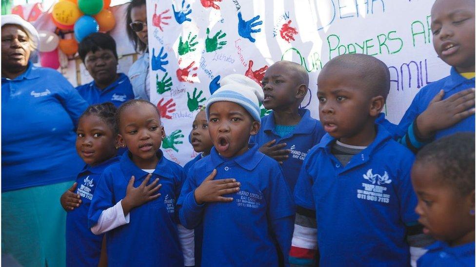 A choir of children dressed in identical blue shirts from the Thand Uxolo Day Care centre in Pretoria sings for Mr Mandela, their hands against their hearts