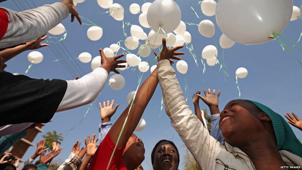 Children raise toward the sky after releasing the white balloons outside the hospital in Pretoria (27 June 2013)