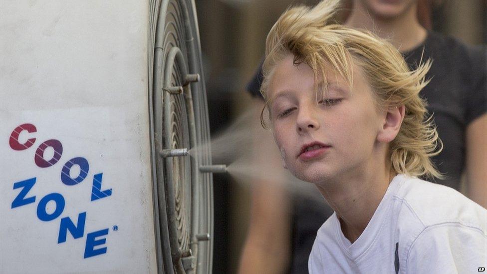 A boy stands in front of a misting fan in Mesa, Arizona (28 June 2013)