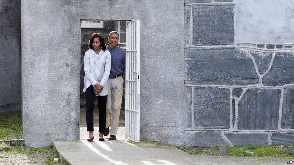 US President Barack Obama and First Lady Michelle Obama walk through a prison yard as they tour Robben Island.