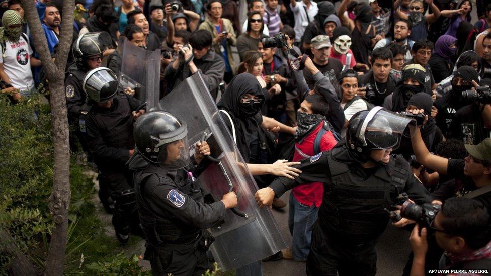 Mexican police try to control a crowd during a march to protest against reform of Pemex, Monday, 1 July