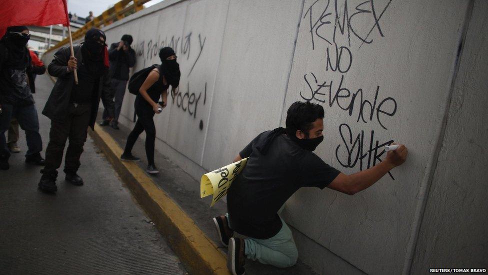 A demonstrator writes graffiti, which reads "Pemex is not for sale", during a protest against the privatisation of the state oil monopoly Pemex in Mexico City, 1 July