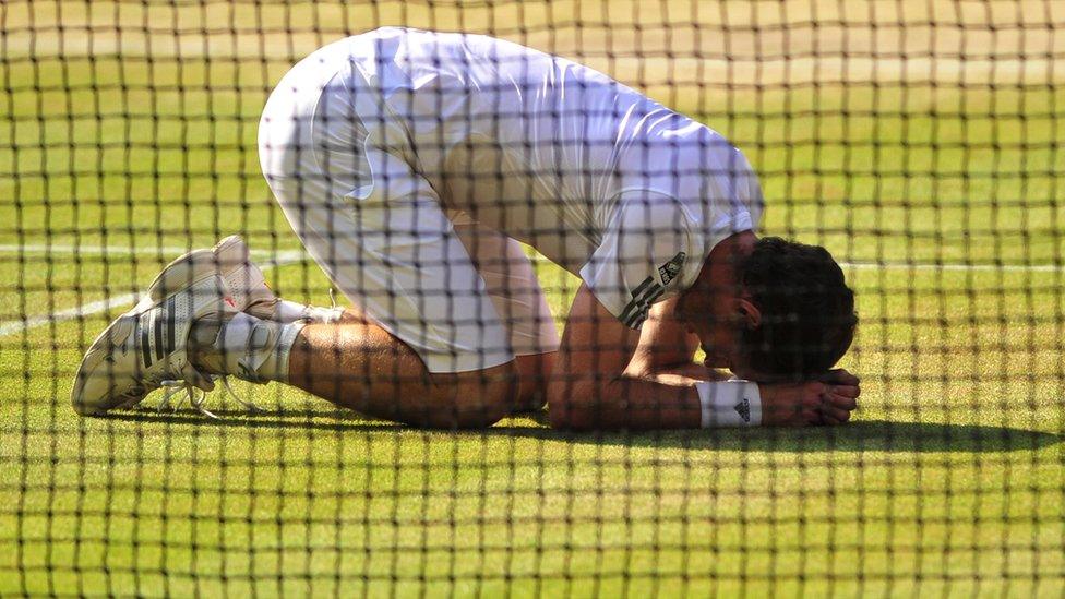 Andy Murray kneels on the turf after securing victory