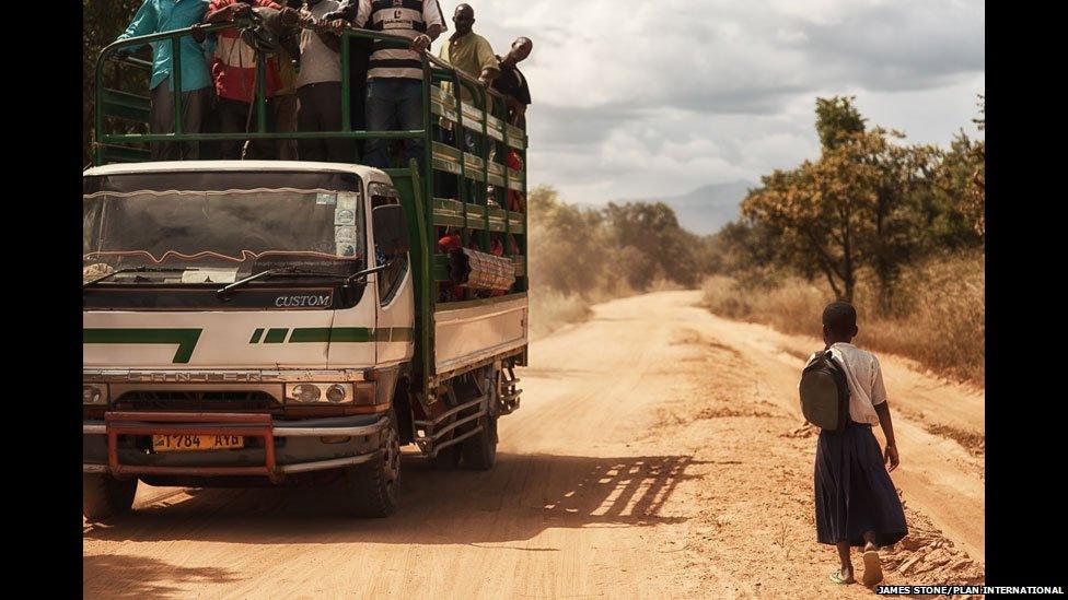 A truck passes Tanzanian schoolgirl Sylvia on a main road
