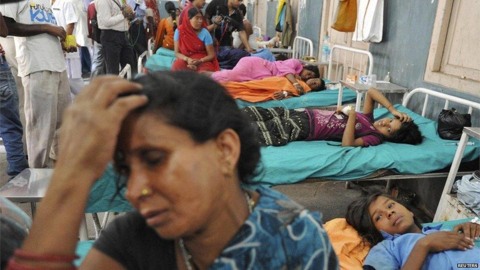 Mother Asha Devi sits with her hand on her head next to her sick daughter at a hospital in the eastern city of Patna on 17 July 2013