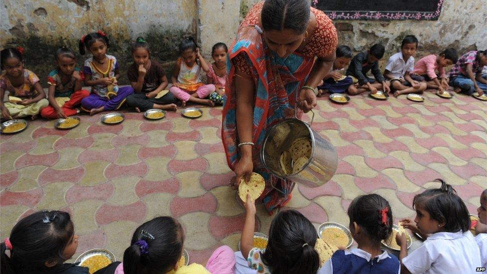 Indian schoolchildren receive their free mid-day meal at a school in Ahmedabad on 17 July 2013