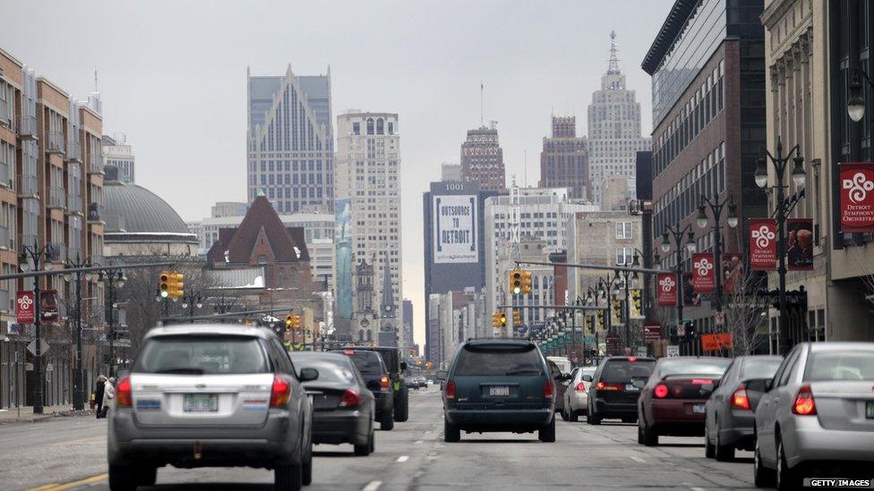 Cars in downtown Detroit in February 2013, with a sign on a skyscraper saying 'Outsource to Detroit'.