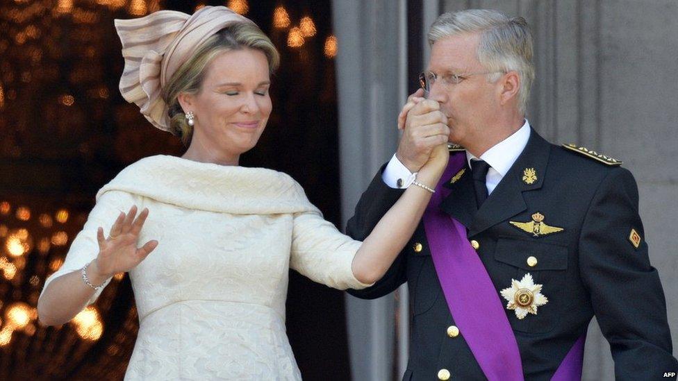 King Philippe kisses the hand of his wife Queen Mathilde as they greet crowds from the balcony of the Royal Palace in Brussels, 21 July 2013