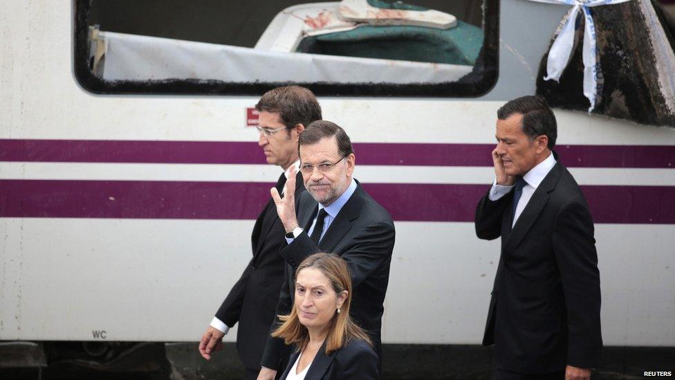 Mariano Rajoy walks past the damaged train