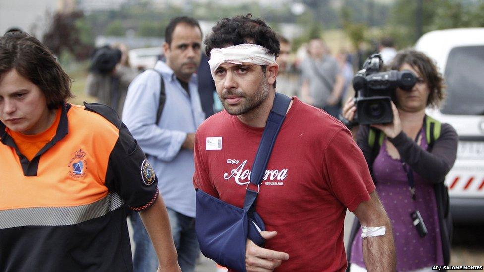 A man with head bandage and right arm in a sling accompanied by a rescue worker