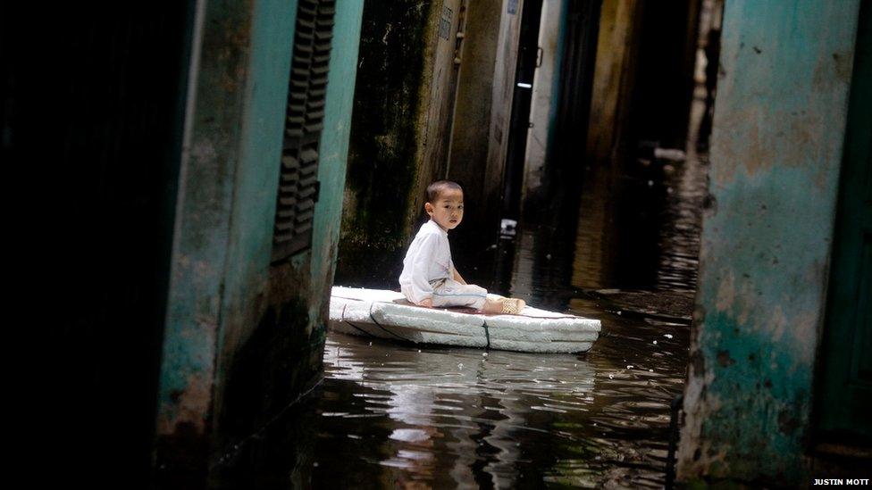 Vu Giam An, 3, rests on a homemade styrofoam raft outside his house during the heavily flooded Hoang Mai Distict of Hanoi, Vietnam on Nov. 4, 2008.