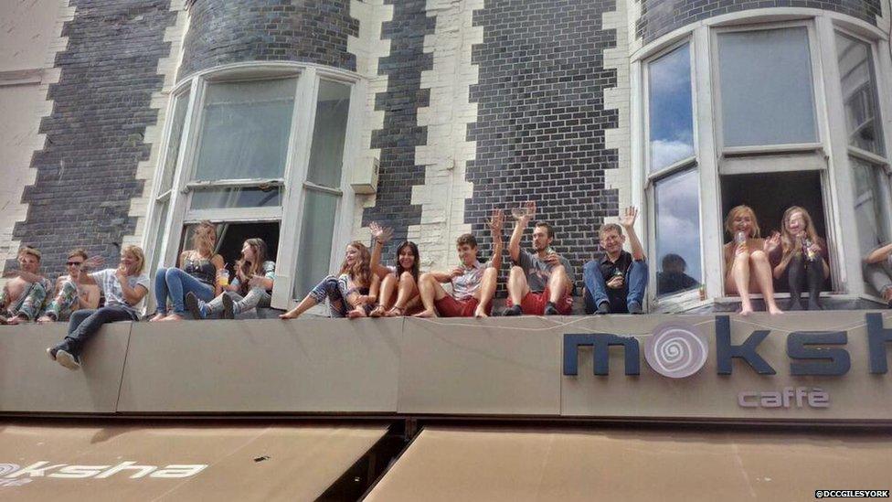 People watching the parade from windows above a cafe