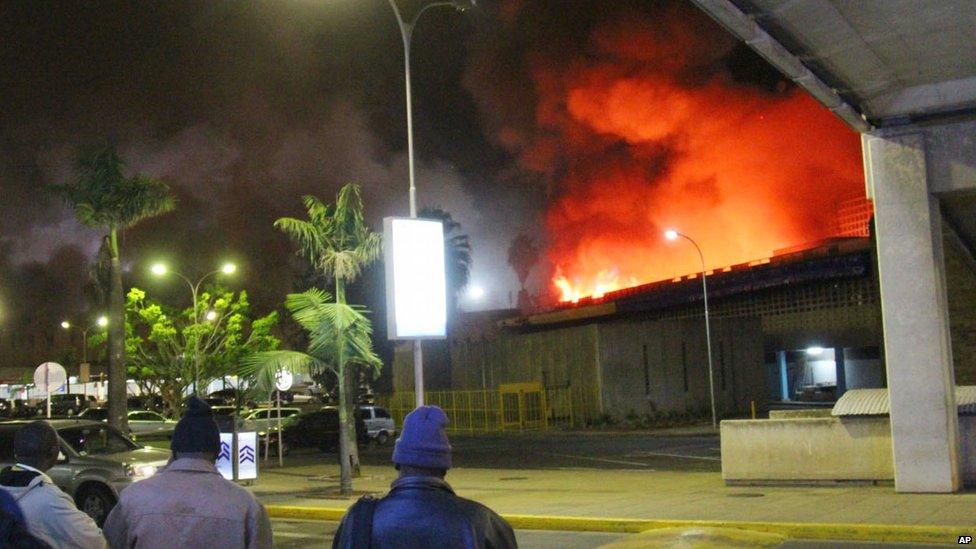 People watch a large blaze raging at the Jomo Kenyatta International Airport in Nairobi, Kenya, early Wednesday 7 Aug 2013.